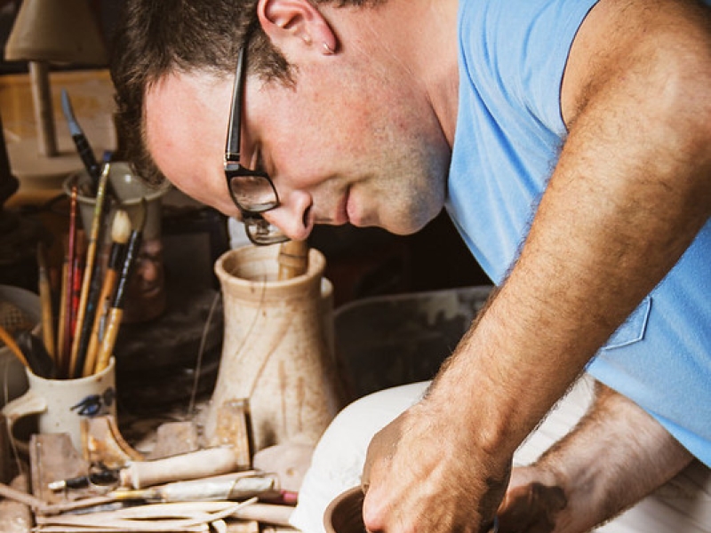 Potter Michael Stanley working on pottery wheel in studio