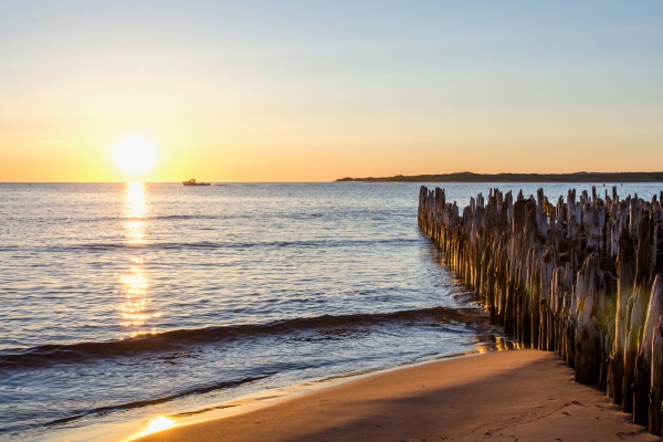 View of old piers at St. Peters Harbour at sunset with fishing boat in distance