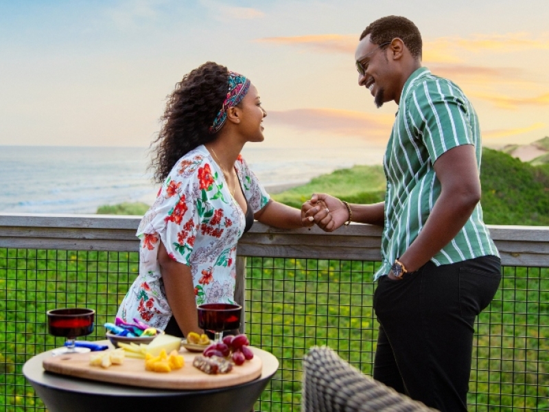 Couple watch sunset from deck of seaside cottage 