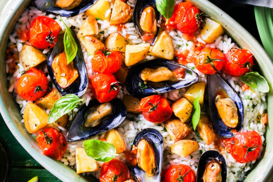 One dish meal of rice, steamed mussels, cherry tomatoes and potatoes in a cream sauce