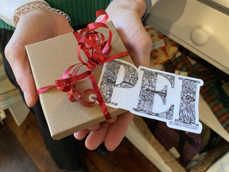 A female holds a small package with red ribbon and a PEI sticker